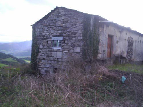 Vista de las fachadas lateral y frontal de la casa para rehabilitar en la parcela en la que se ubica. - Se abre en una nueva ventana